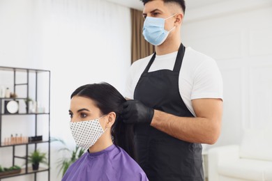 Photo of Professional stylist working with client in salon. Hairdressing services during Coronavirus quarantine