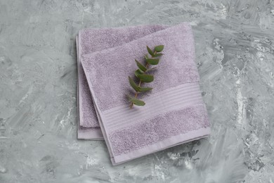 Photo of Violet terry towel and eucalyptus branch on grey table, top view