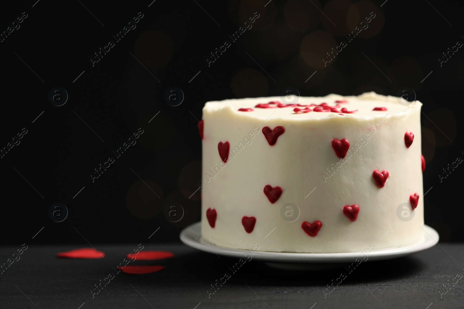 Photo of Bento cake with red cream hearts on black table, space for text. St. Valentine's day surprise