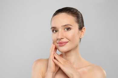 Portrait of beautiful young woman with perfect skin on grey background. Spa treatment