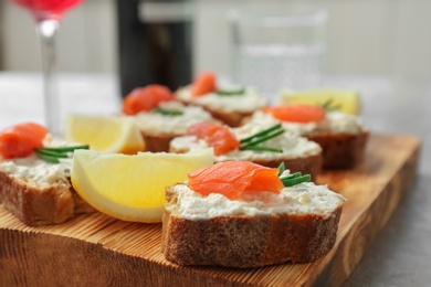 Photo of Sandwiches with fresh sliced salmon fillet on wooden board, closeup