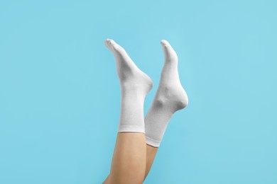 Photo of Woman in stylish white socks on light blue background, closeup