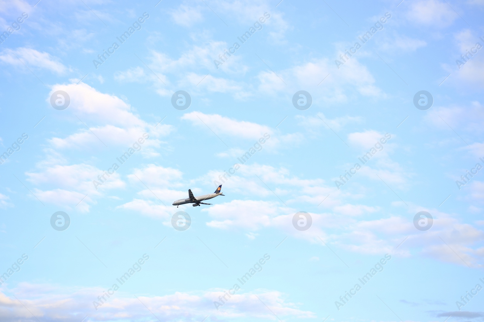 Photo of Modern airplane flying in blue cloudy sky. Space for text