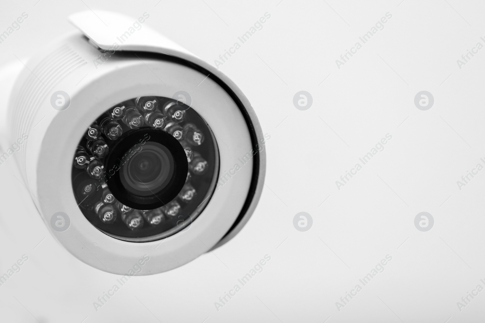 Photo of Modern CCTV security camera on white wall. Space for text