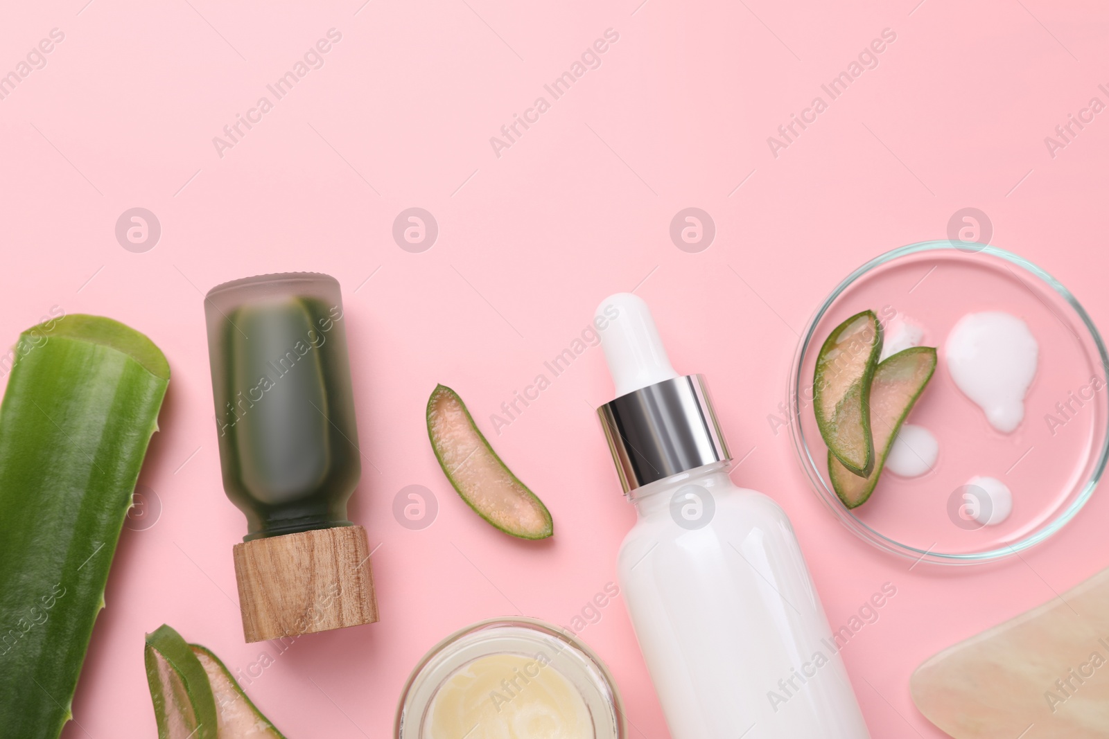 Photo of Cosmetic products and cut aloe leaves on pink background, flat lay. Space for text