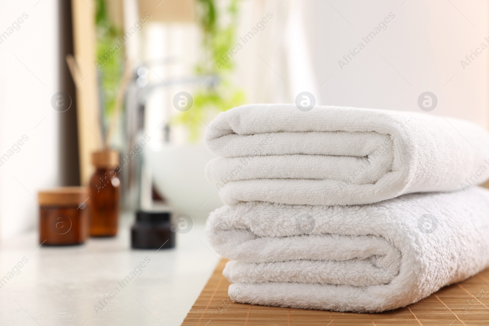 Photo of Stacked soft towels on white table in bathroom. Space for text