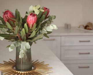 Bouquet with beautiful protea flowers on countertop in kitchen, space for text. Interior design