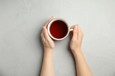 Photo of Woman with cup of tea at light table, top view