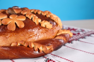 Rushnyk with korovai on light blue background, closeup. Ukrainian bread and salt welcoming tradition