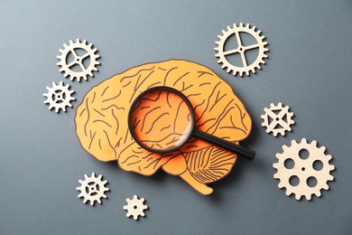 Amnesia. Paper cutout of human brain, cogwheels and magnifying glass on grey background, flat lay