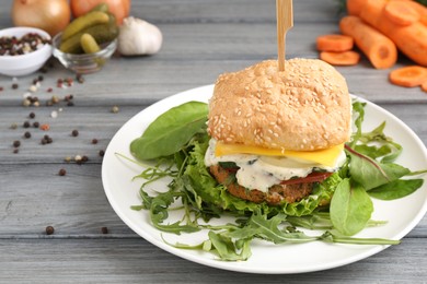 Photo of Delicious vegetarian burger served on grey wooden table