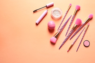 Flat lay composition with makeup brushes on orange background. Space for text