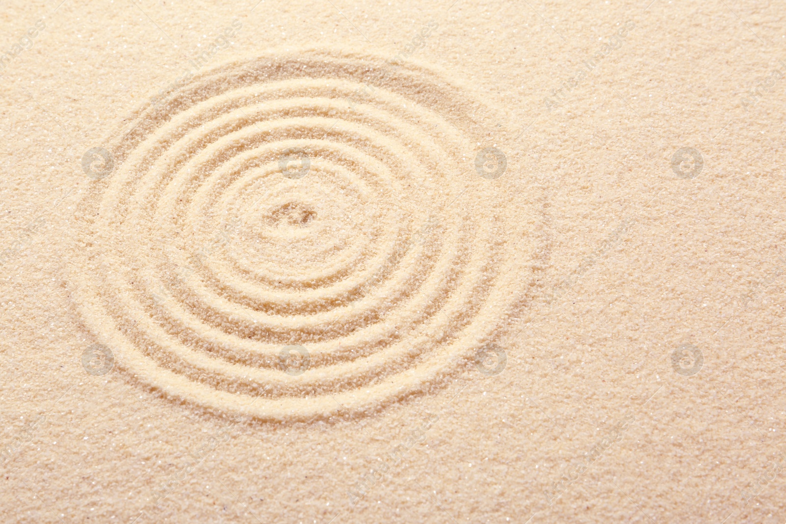 Photo of Zen rock garden. Circle pattern on beige sand