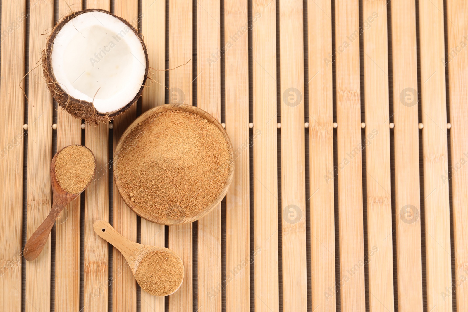 Photo of Coconut sugar, spoons, plate and fruit on wooden table, flat lay. Space for text