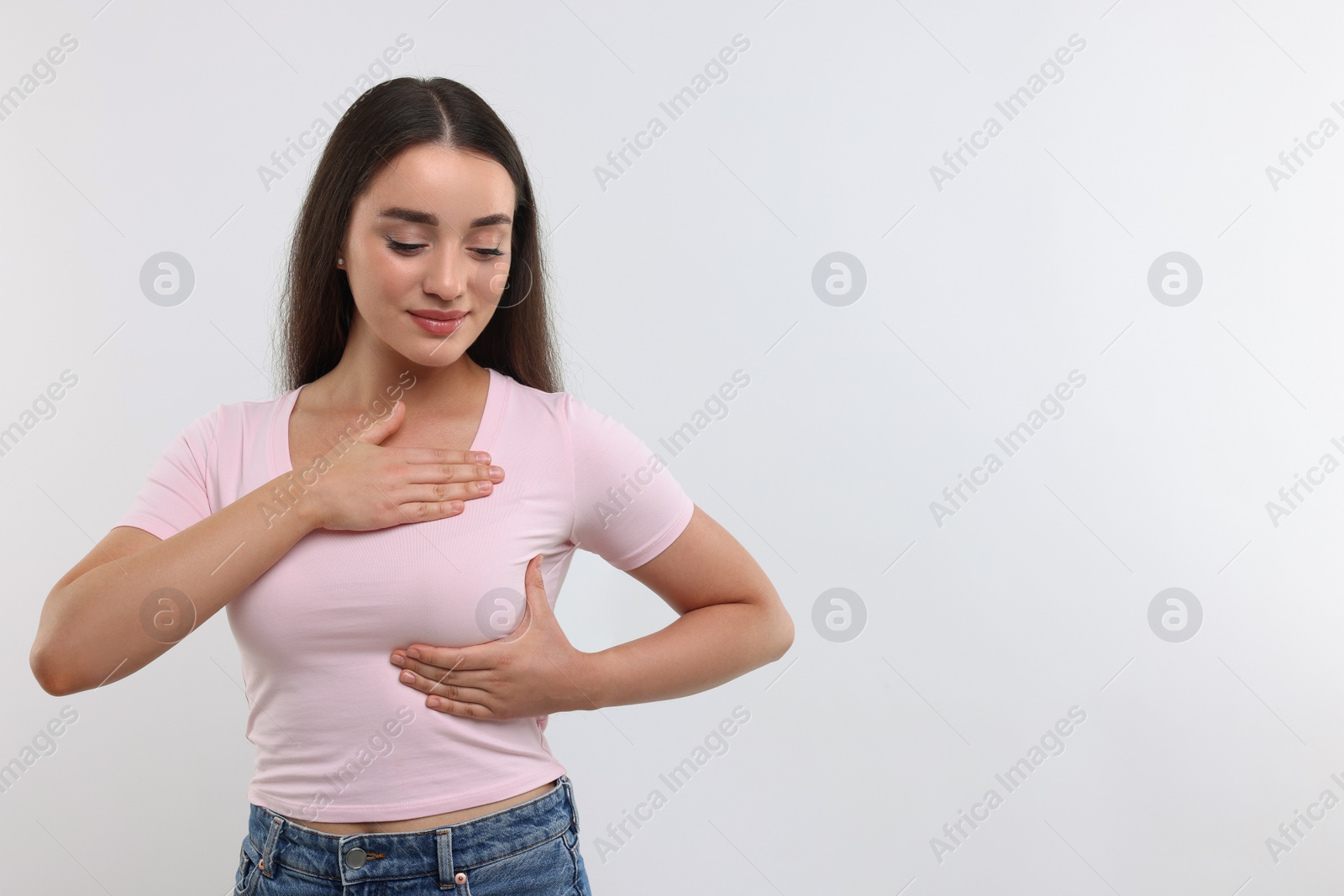 Photo of Beautiful young woman doing breast self-examination on white background, space for text