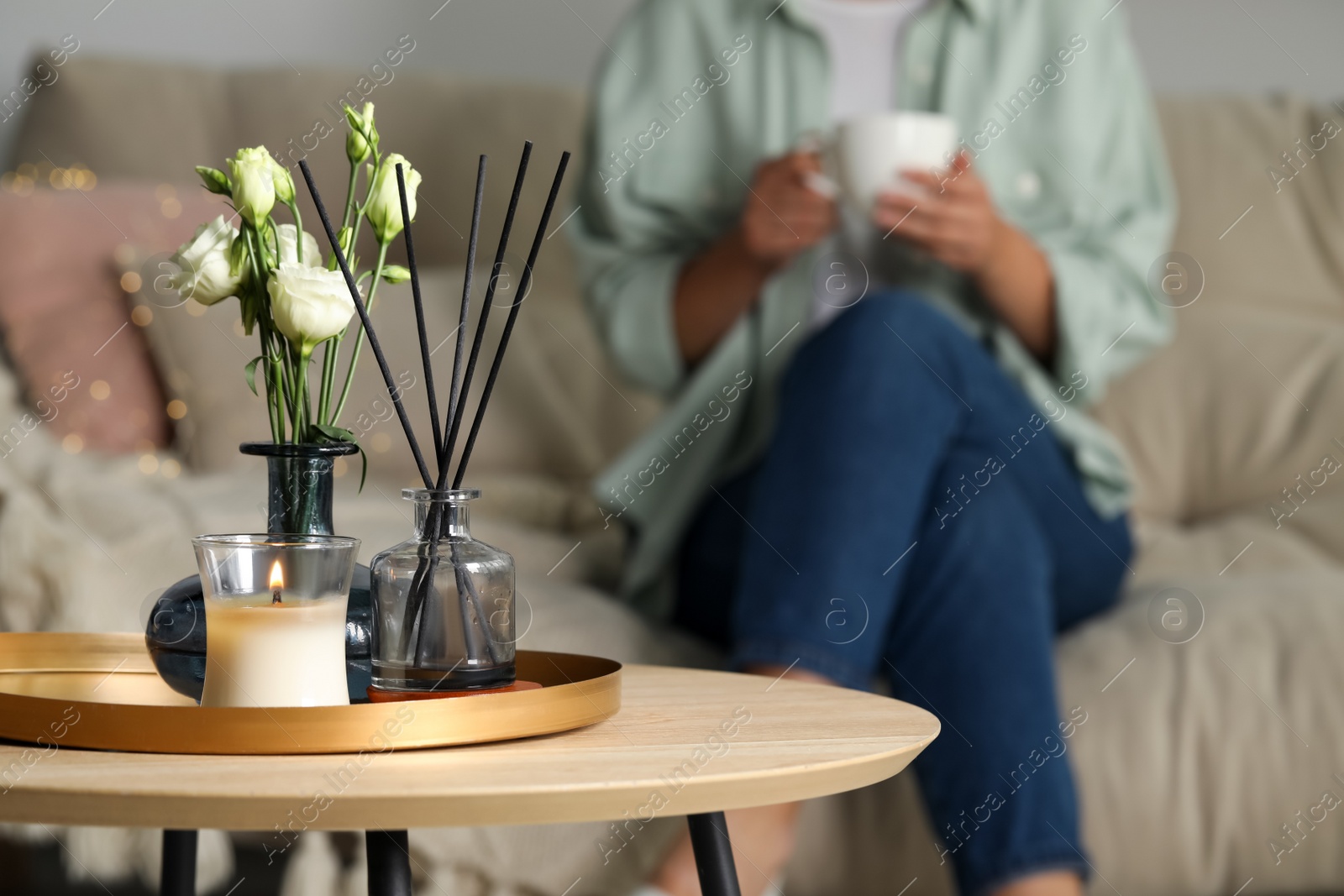 Photo of Home decor on wooden table and woman sitting in living room