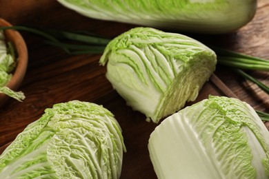 Photo of Whole and cut fresh Chinese cabbages on wooden table, closeup