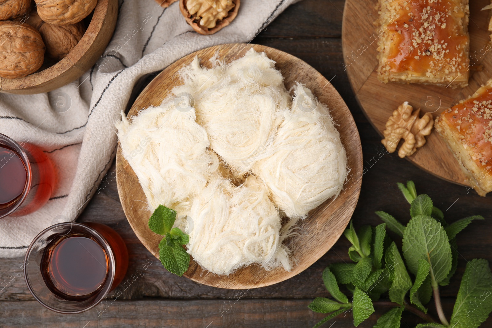 Photo of Eastern sweets. Tasty Iranian pashmak and tea on wooden table, flat lay