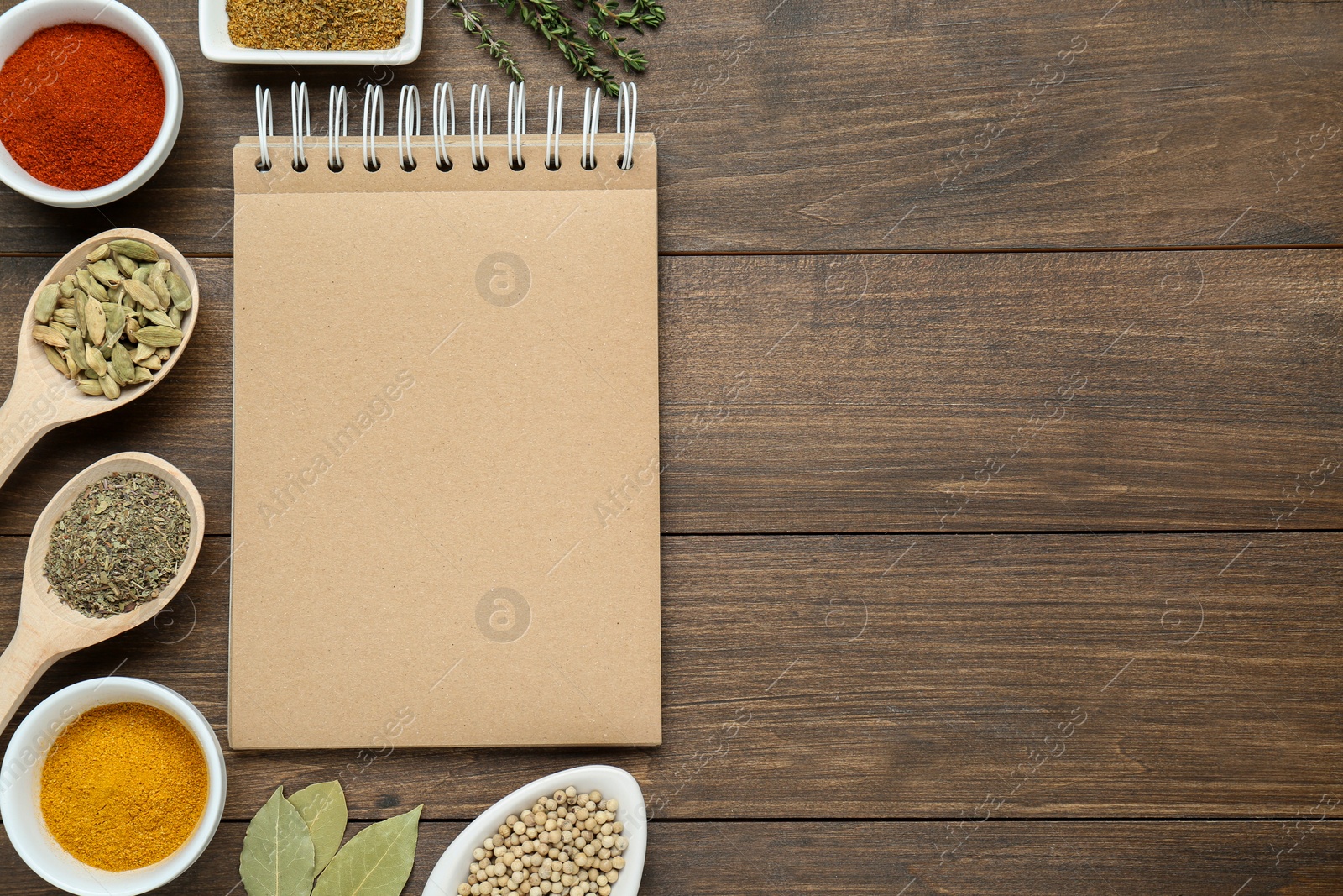 Photo of Blank recipe book and different ingredients on wooden table, flat lay. Space for text