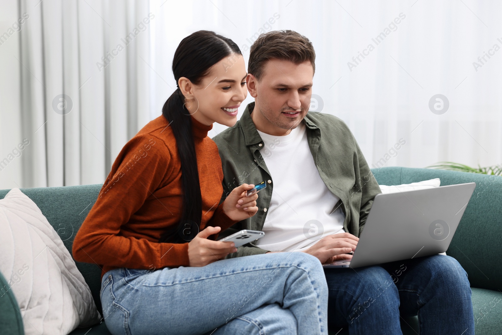 Photo of Happy couple with credit card and gadgets shopping online together at home