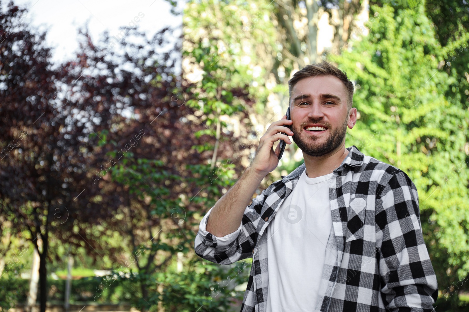 Photo of Young man talking on smartphone in park