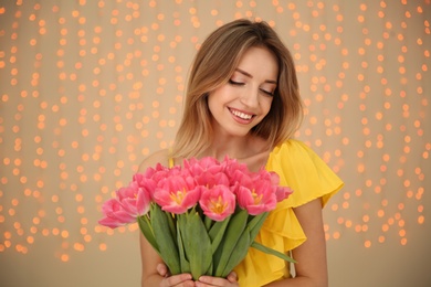 Photo of Portrait of smiling young girl with beautiful tulips on blurred background. International Women's Day