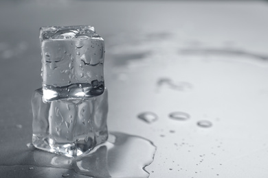 Photo of Crystal clear ice cubes with water drops on grey table, closeup. Space for text