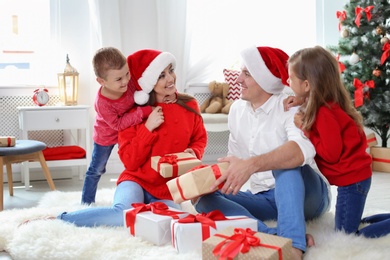 Photo of Happy parents with children and gifts at home. Celebrating Christmas