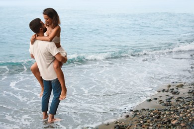 Photo of Happy young couple having fun on beach near sea. Space for text