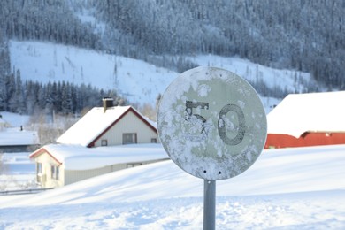 Post with road sign Maximum Speed 50 on snowy street, space for text