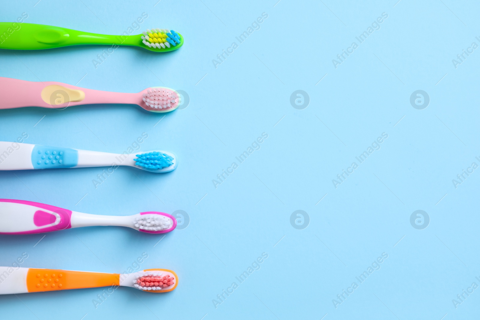 Photo of Different toothbrushes and space for text on light blue background, flat lay