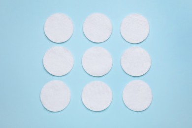 Many cotton pads on light blue background, flat lay