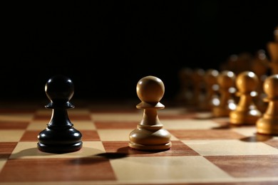 Photo of Black and white pawns in middle of wooden chess board against dark background