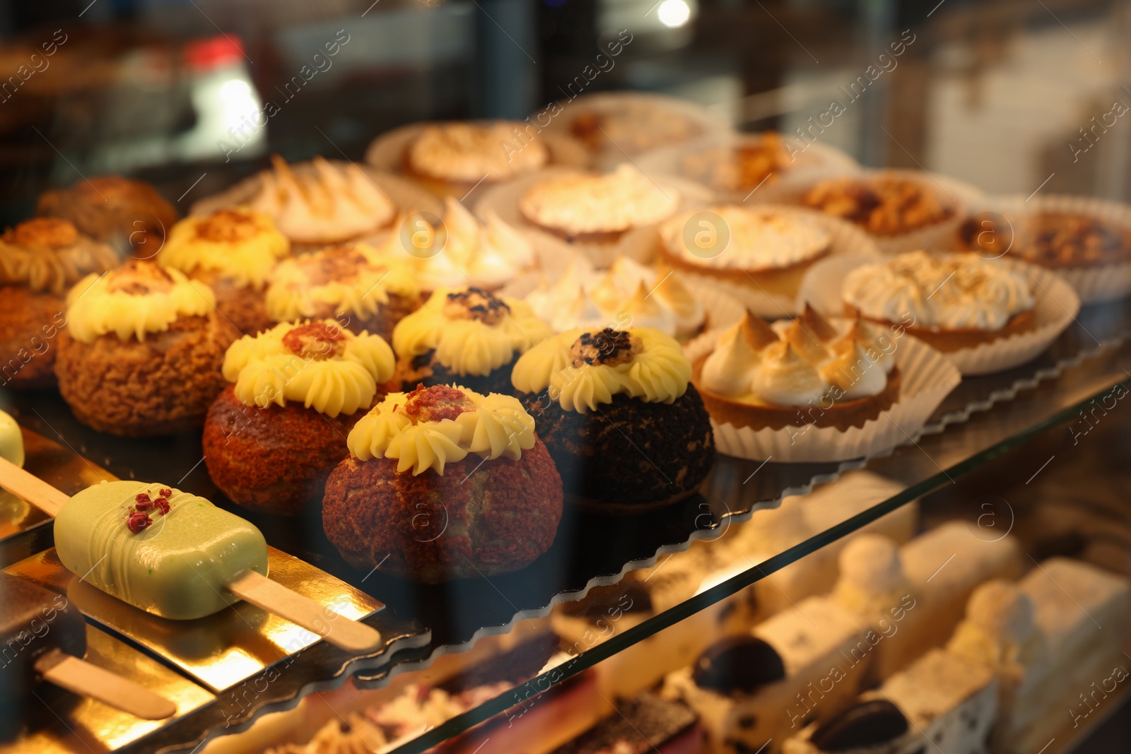 Photo of Different tasty desserts on counter in bakery shop, closeup