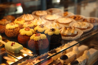 Different tasty desserts on counter in bakery shop, closeup