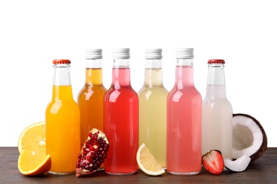 Delicious kombucha in glass bottles, fresh fruits and coconut on wooden table against white background