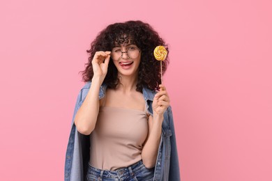 Beautiful woman with lollipop on pink background