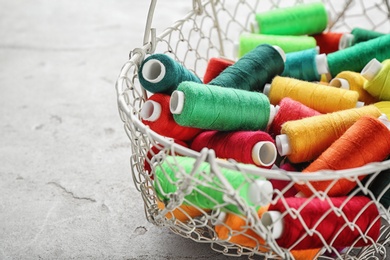 Photo of Metal basket with color sewing threads on grey background