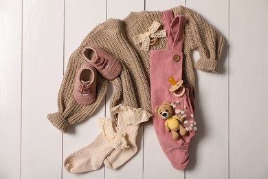 Flat lay composition with children's clothes, shoes and toy on white wooden table