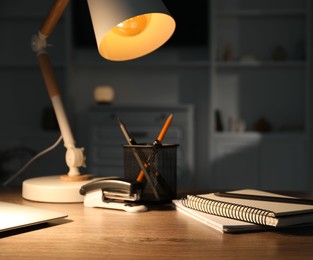 Stylish lamp and stationery on wooden table indoors