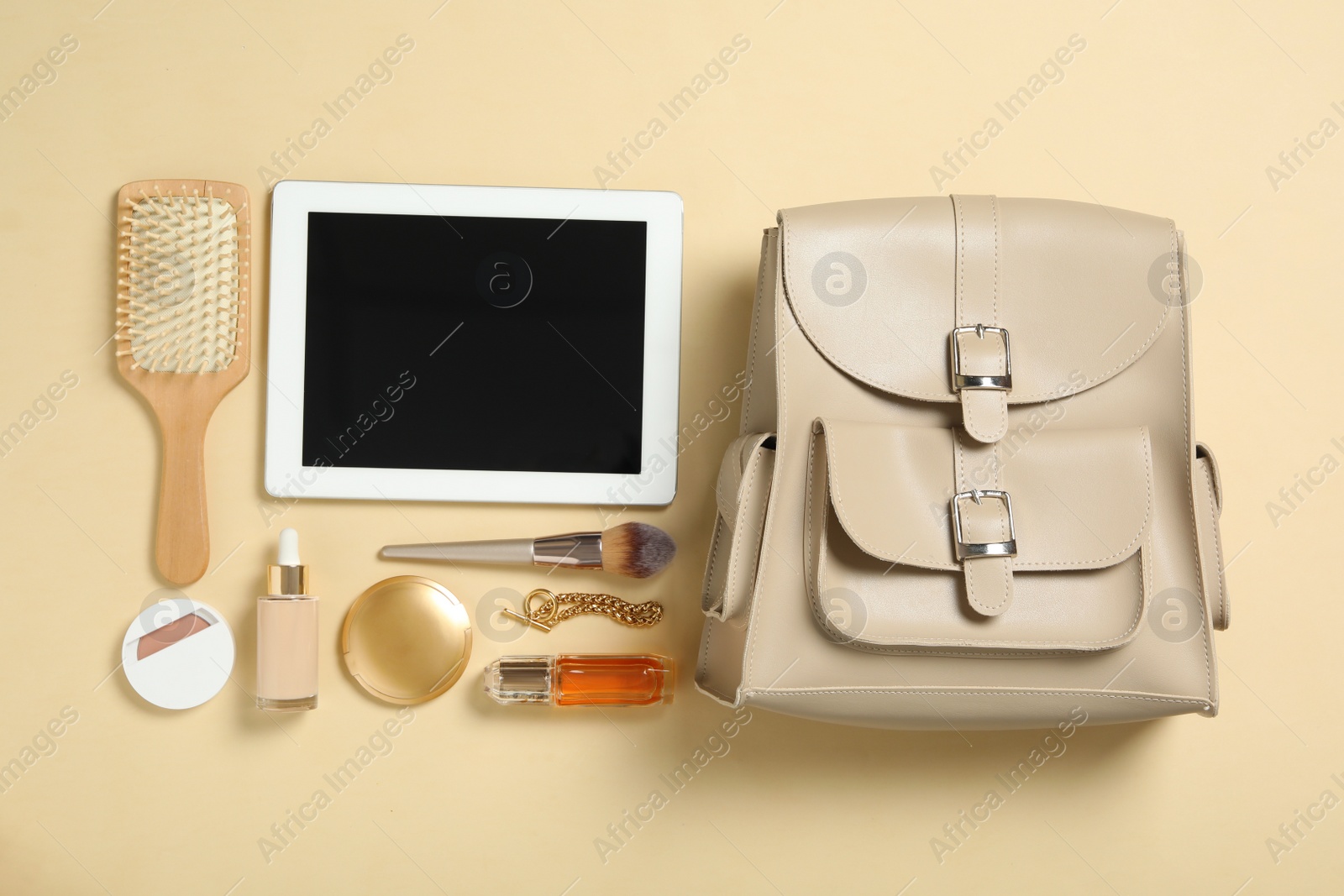 Photo of Stylish urban backpack with different items on beige background, flat lay