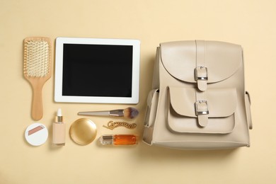 Photo of Stylish urban backpack with different items on beige background, flat lay