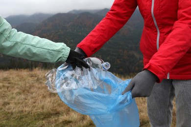 Photo of People with trash bag collecting garbage in nature, closeup