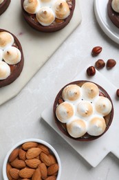 Delicious salted caramel meringue tarts and nuts on light grey marble table, flat lay