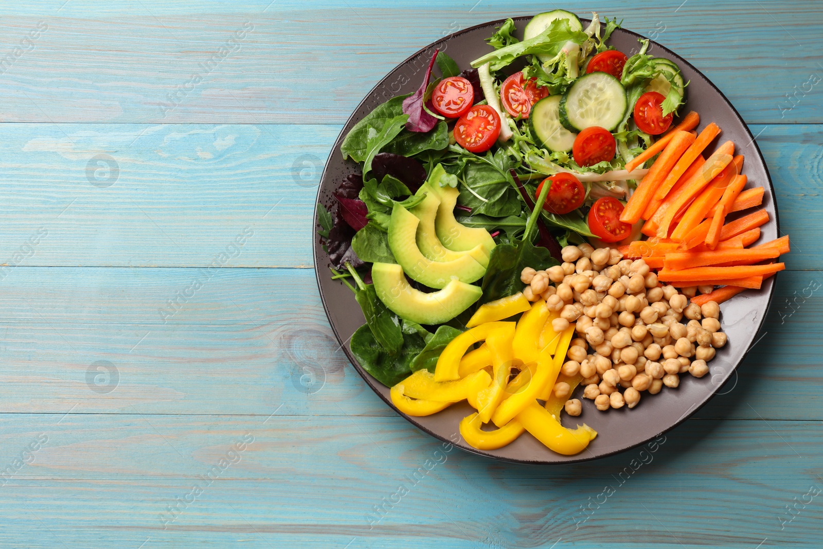 Photo of Balanced diet and vegetarian foods. Plate with different delicious products on light blue wooden table, top view. Space for text