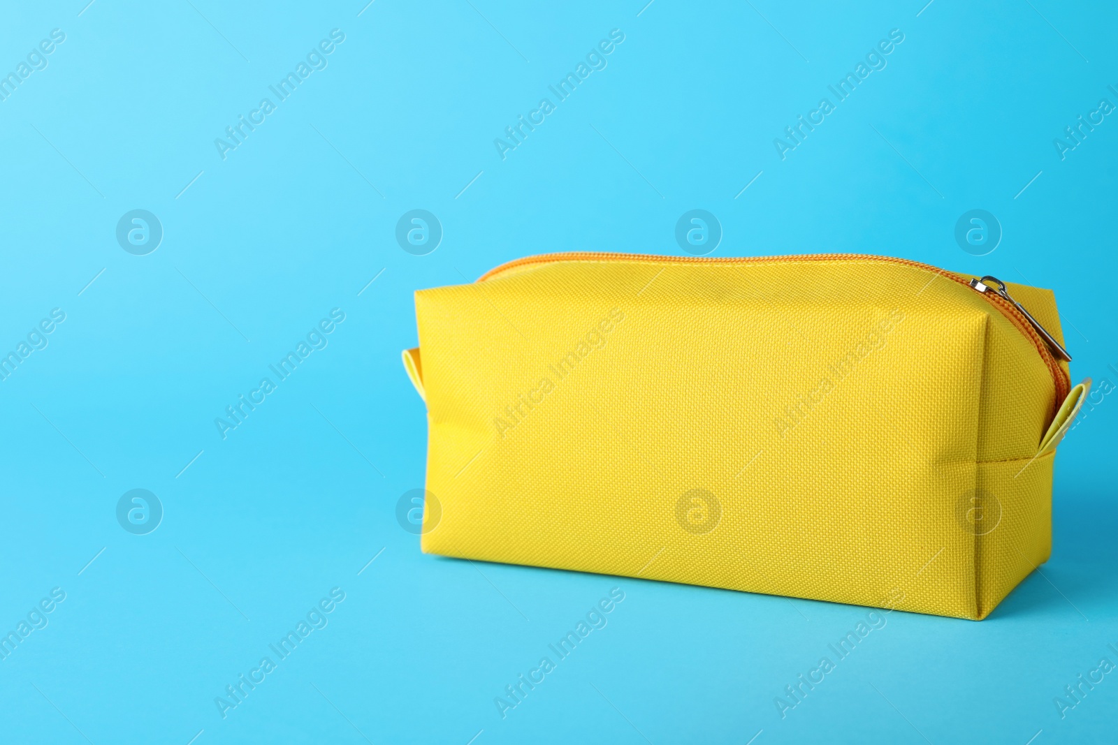 Photo of Yellow cosmetic bag on light blue background. Space for text