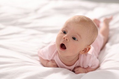 Cute little baby lying on white sheets, space for text