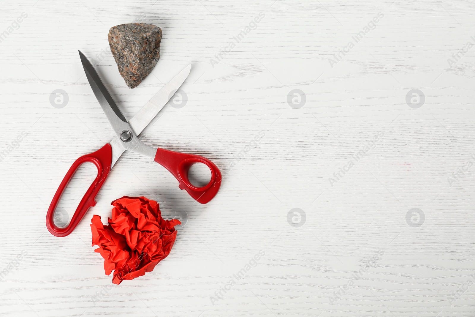 Photo of Flat lay composition with rock, paper and scissors on white wooden background. Space for text