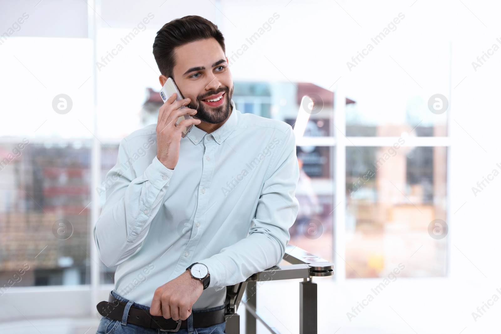 Photo of Portrait of handsome man talking on mobile phone in light room