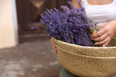 Photo of Woman with basket of beautiful lavender flowers outdoors, closeup. Space for text